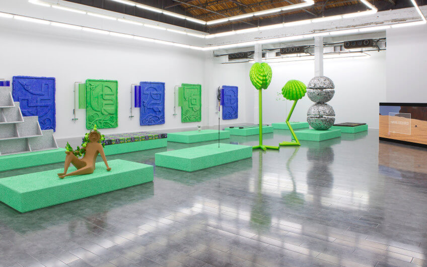 Futuristic sculptures in an immersive art installation space with wall panels at Art Basel.