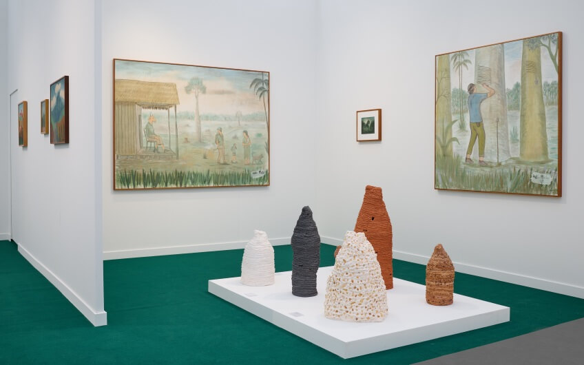 Ceramic sculptures and modern tropical-themed paintings in a curated booth at Art Basel Miami exhibition.
