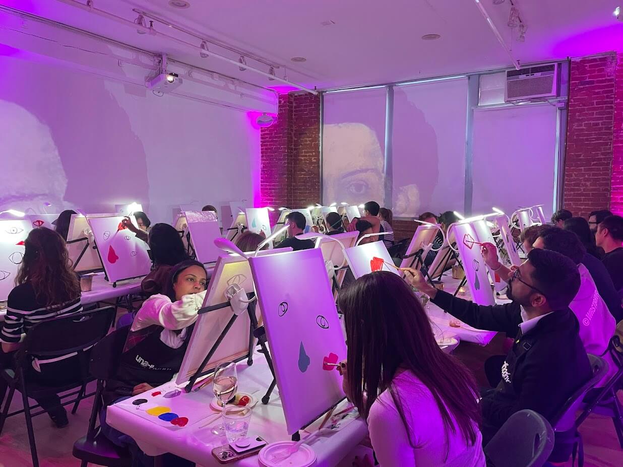 Group of people painting on canvases at an art event