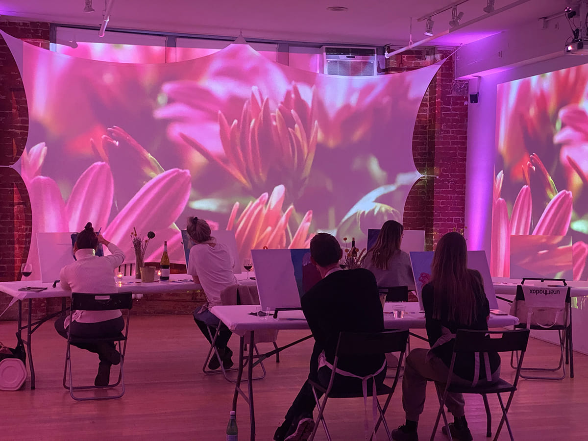 People creating art in a room with projections of flowers